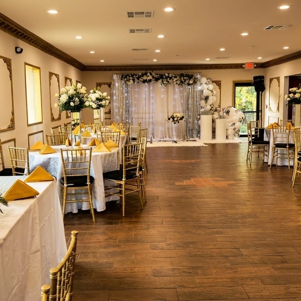 Elegant banquet hall with white and gold decor, round tables, and a sparkling backdrop for events.